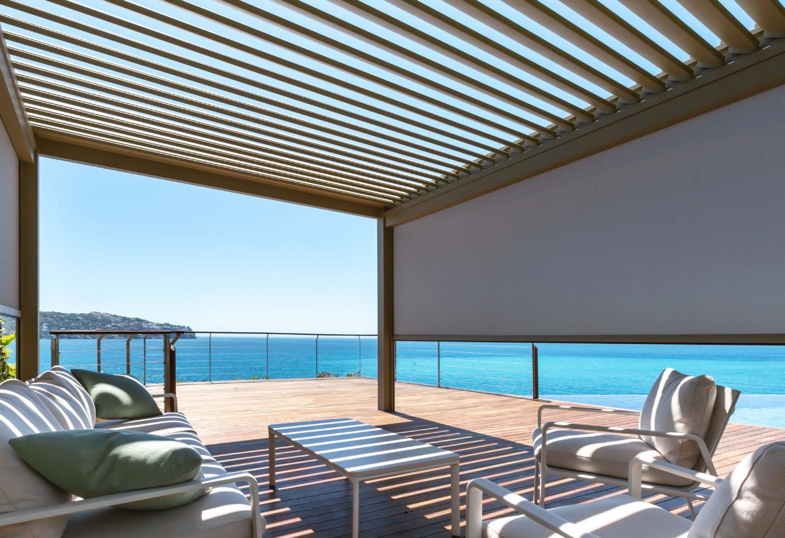 Pérgola bioclimática con cortina de cristal frente al mar