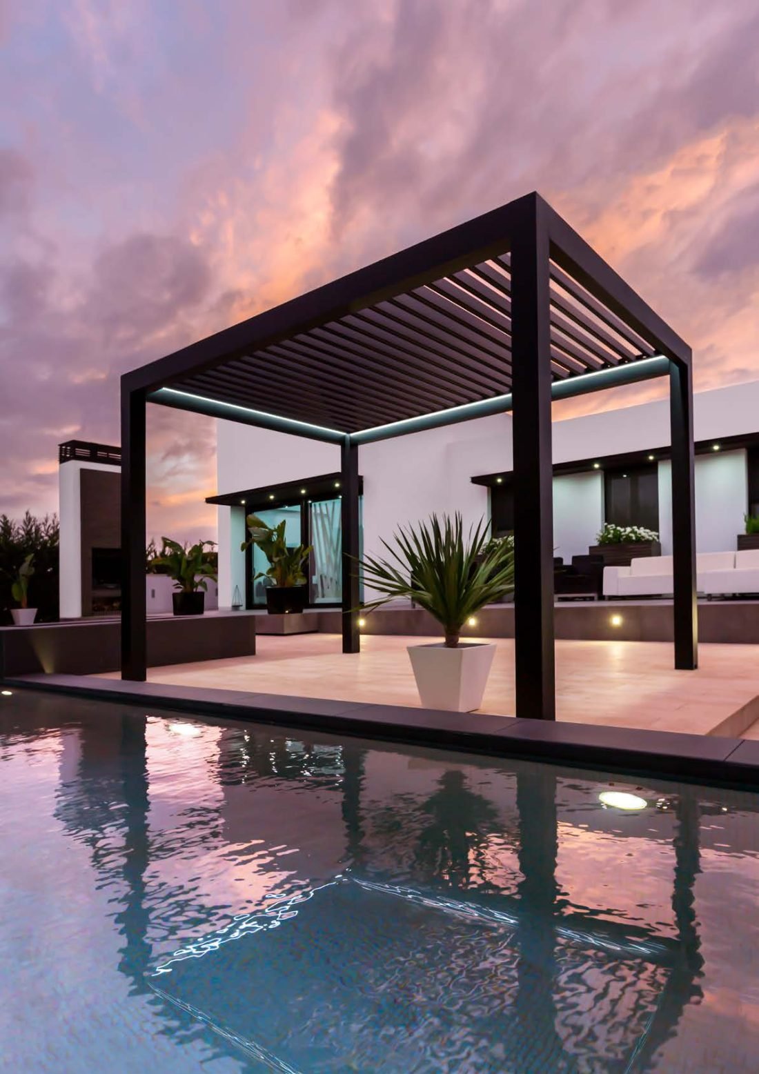 Pérgola bioclimática instalada junto a la piscina al atardecer