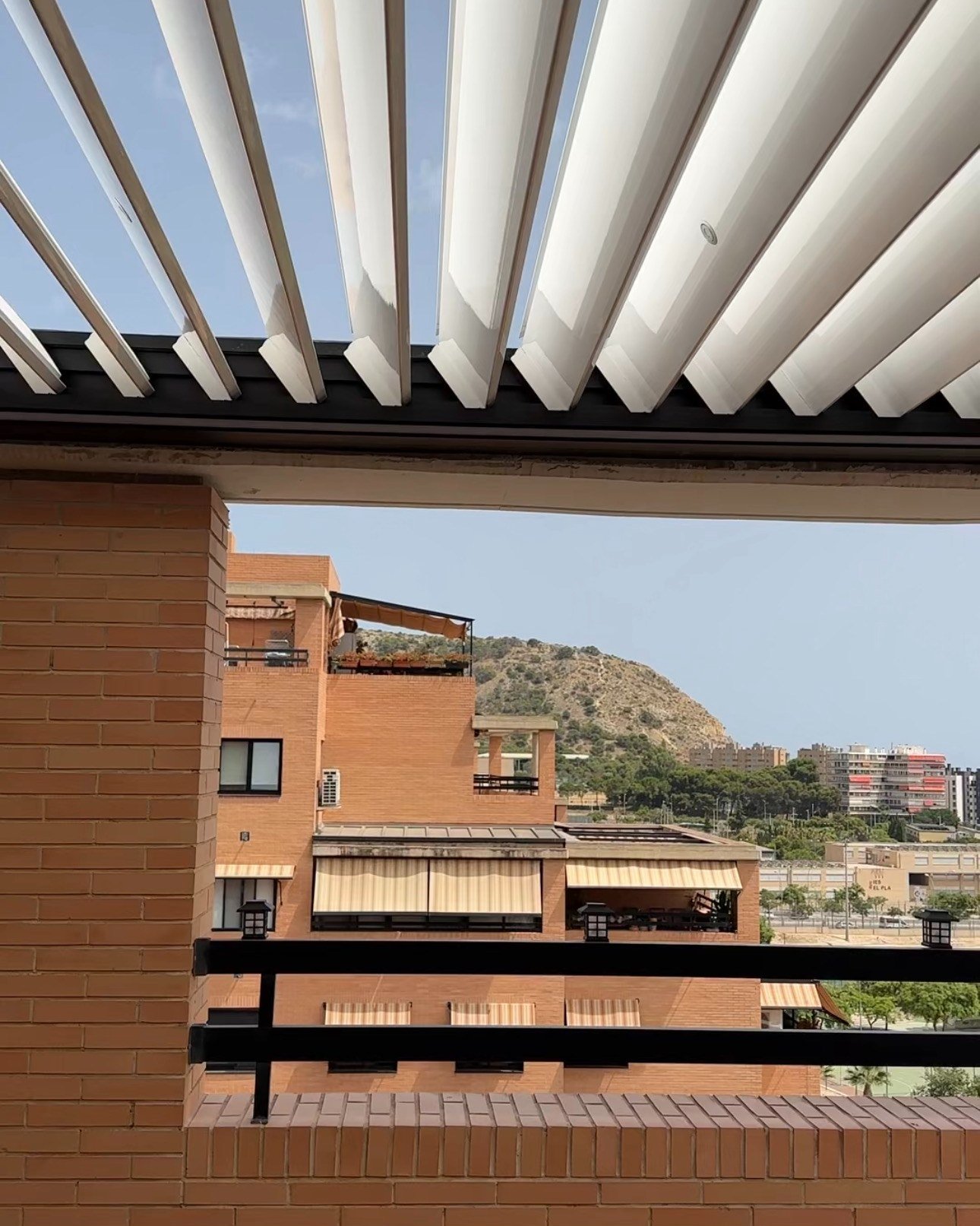 Lamas blancas orientables de la pérgola abiertas en la terraza del ático
