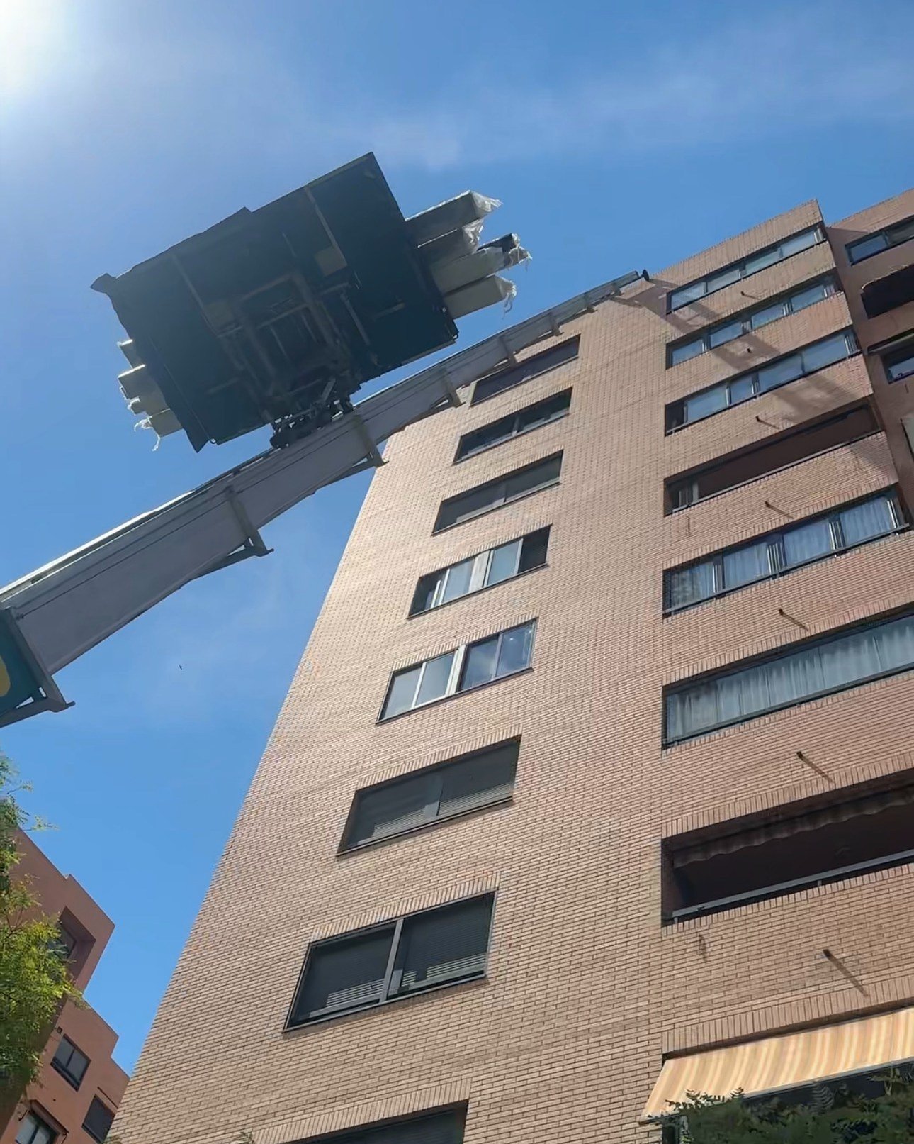 Grúa subiendo la estructura de la pérgola por la fachada del edificio