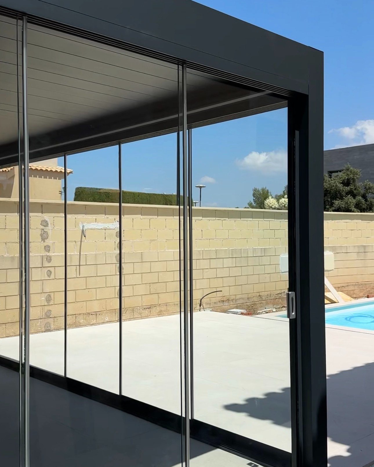 Esquina de una pérgola con cortinas de cristal correderas sin perfiles verticales en Elche