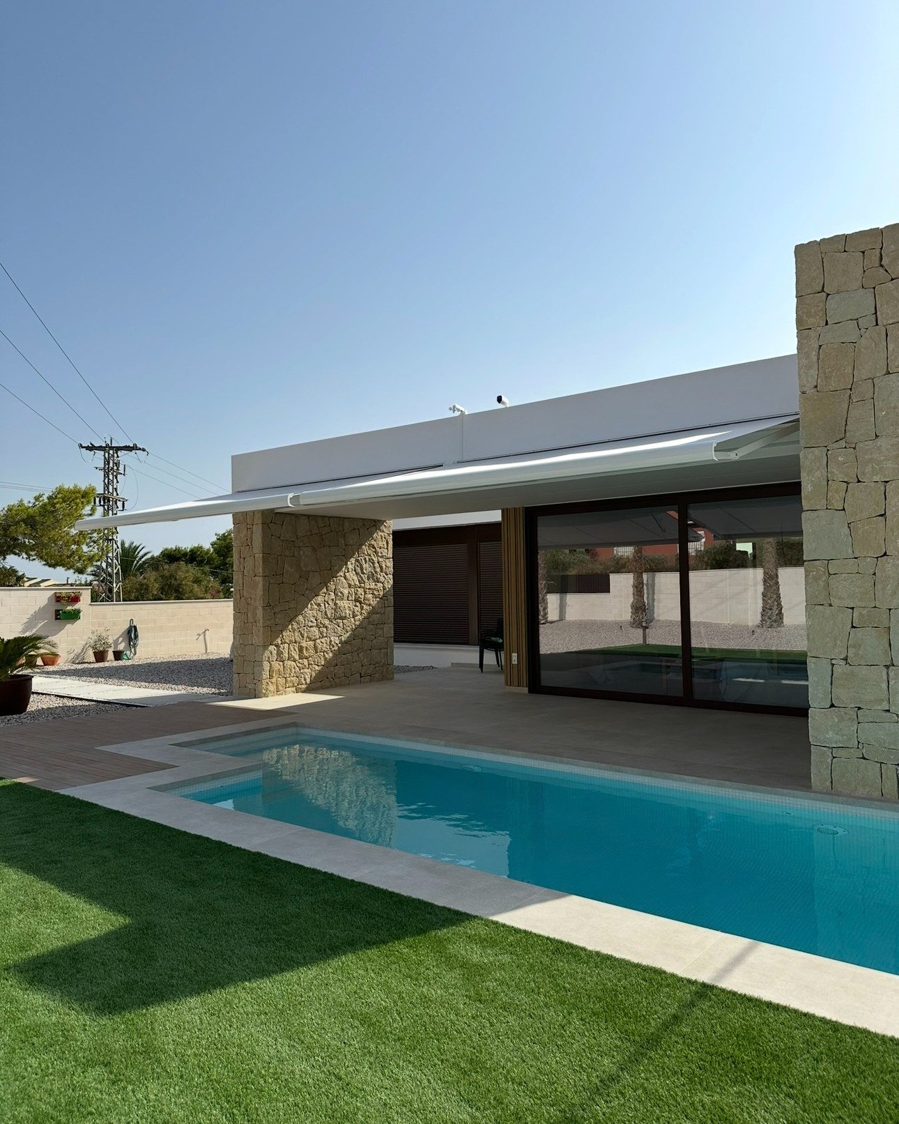 Toldos extensibles blancos sobre el porche de un chalet con piscina